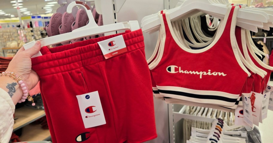 Woman holding up red champion sports bra, and shorts inside target store