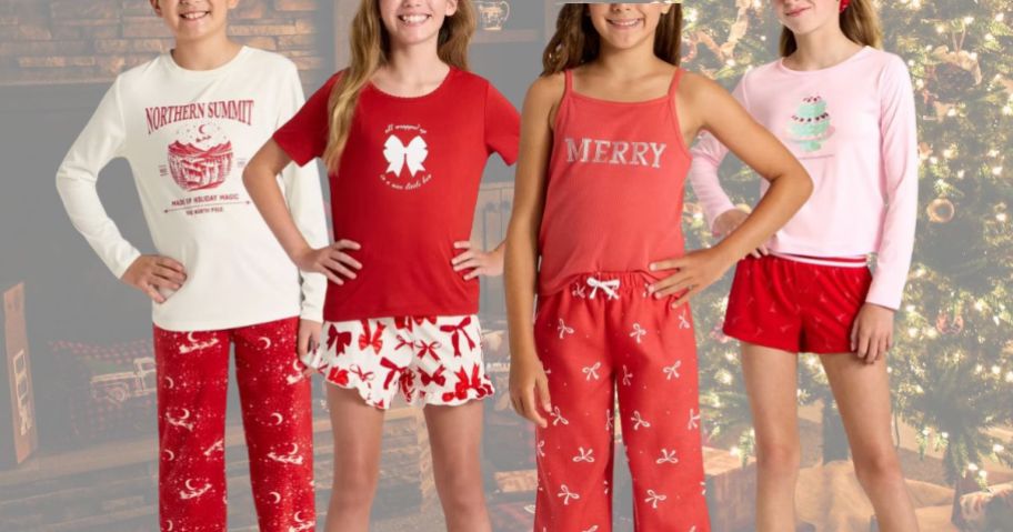 Several kids wearing red and white Christmas outfits in front of a Christmas tree