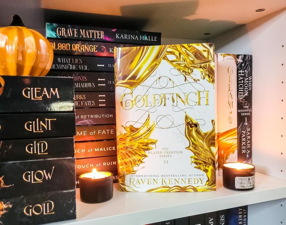 The Plated Prisoner Series on bookshelf with lit candles