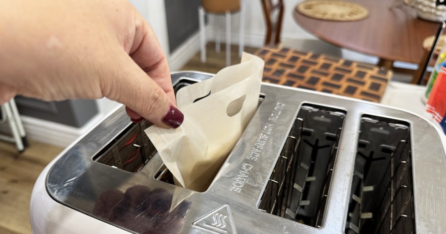 hand grabbing a toaster bag from a toaster