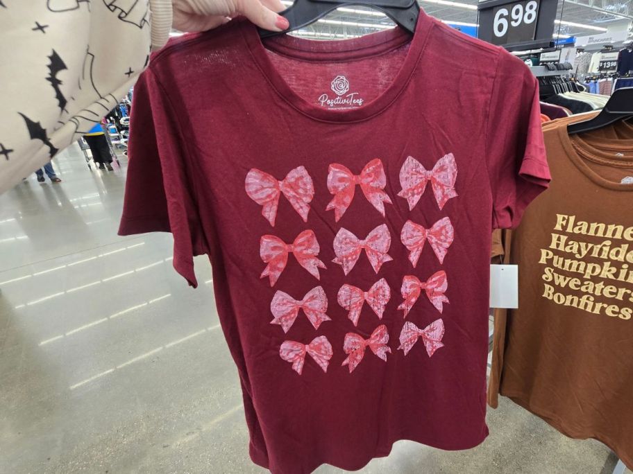 A person holding a pink t- shirt with bows on it