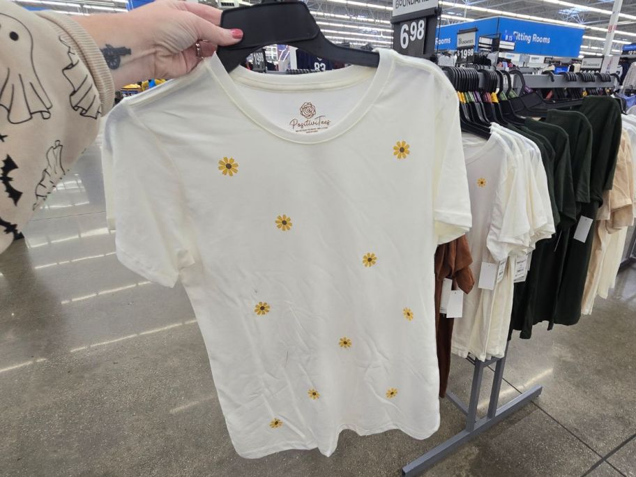A person holding a white t- shirt with daidies on it