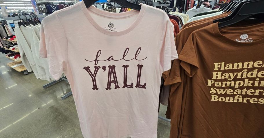 A person holding a white t- shirt with the words "fall y'all" on it