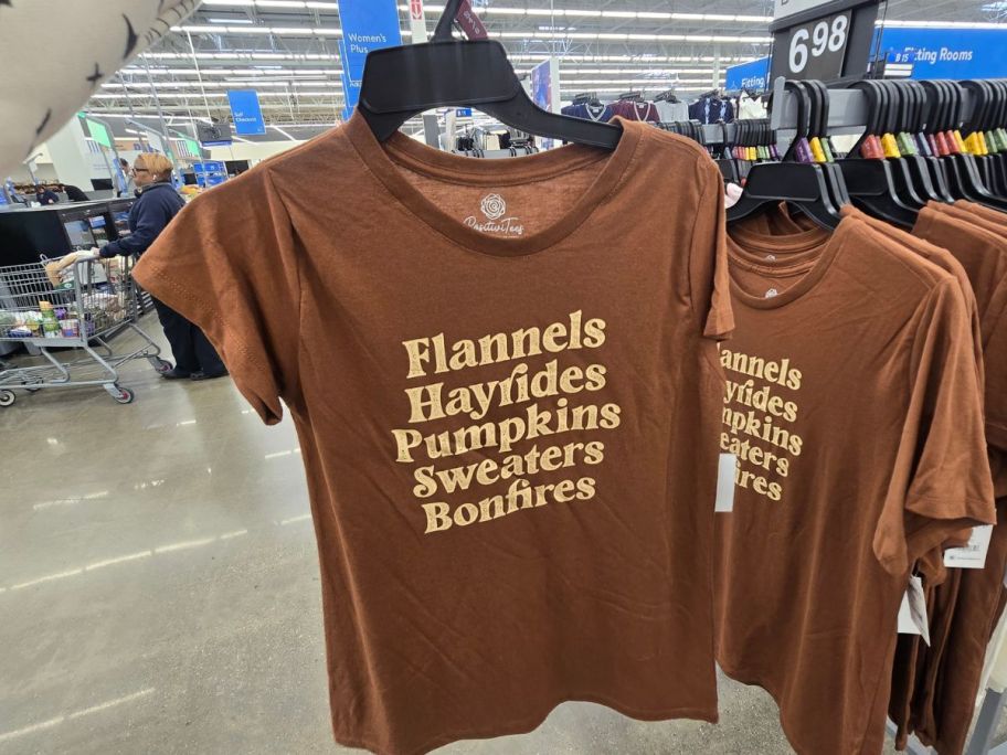 A person holding an orange t- shirt with the word "thankful" on it