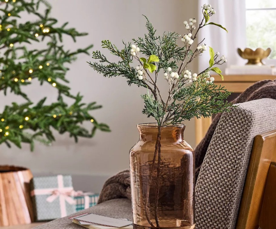 white berry stem in amber vase on table