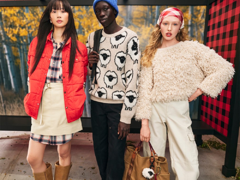 Different women wearing new Woolworths clothing, including sheep, sweaters, red jacket, and tote bag
