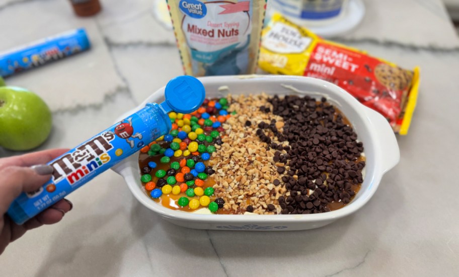 adding m&m's to caramel apple dip