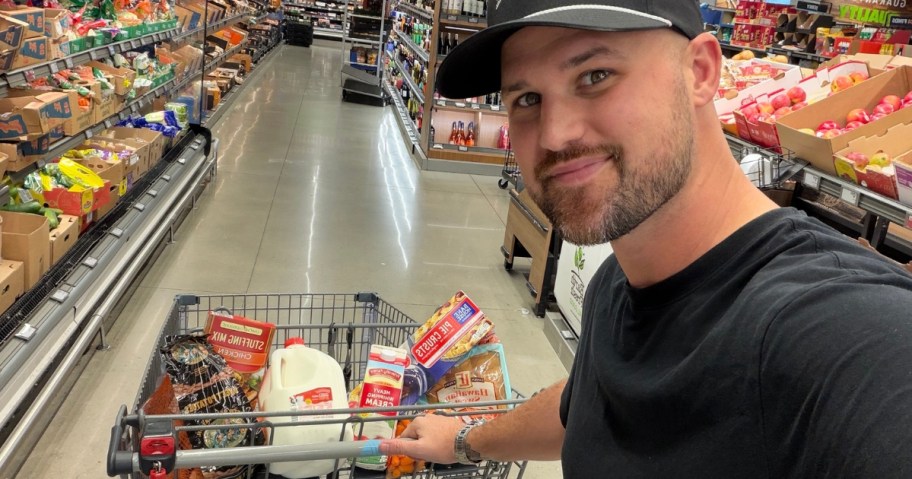 man taking a selfie while pushing a grocery cart through ALDI
