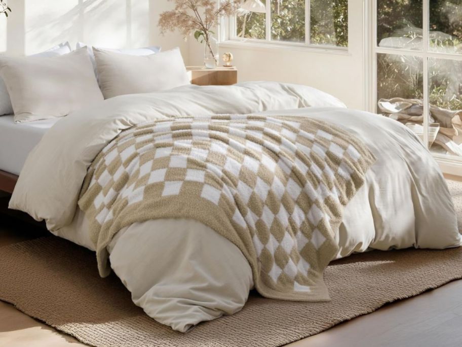 beige and white checkered blanket on comforter on bed