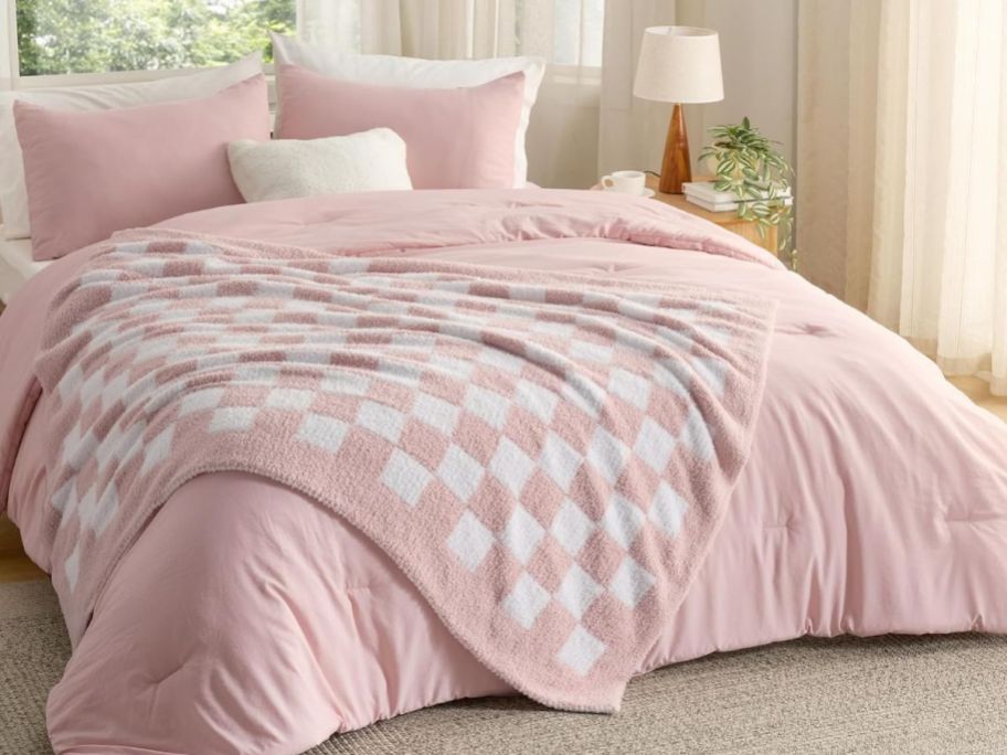 pink and white checkered blanket on comforter on bed