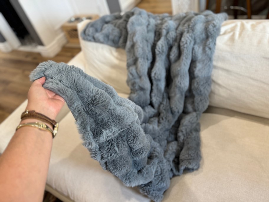 hand holding grey bubble texture faux fur throw blanket on couch