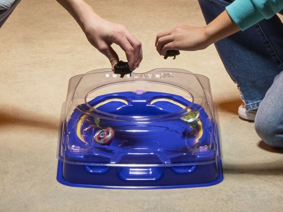 two kids playing with a beyblade arena