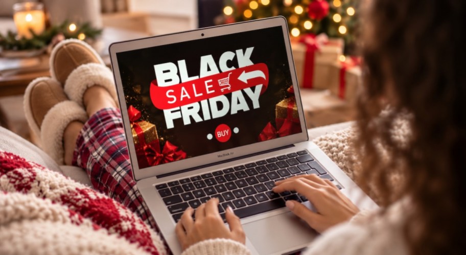 woman sitting on couch with laptop and black friday sign on screen