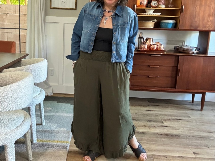 woman wearing green wide leg pants, a black top and a jean jacket