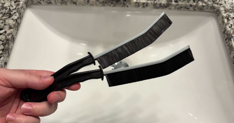 two gap cleaning brushes in hand in bathroom