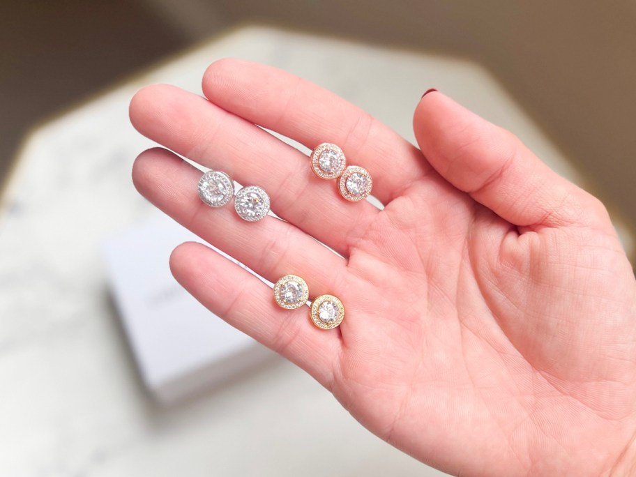 hand holding three pairs of earrings