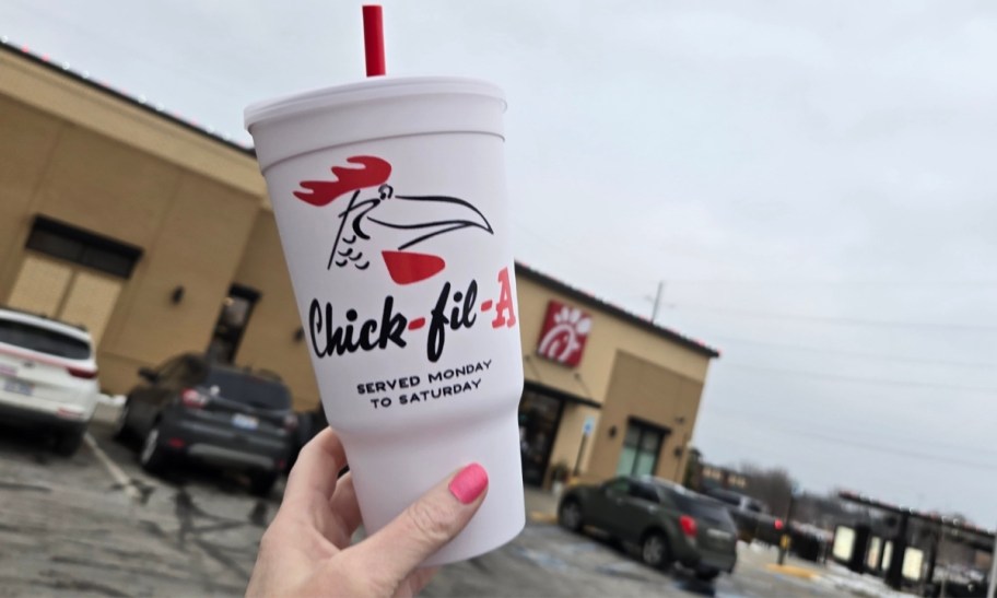 a womans hand holding a chick fil a retro cup