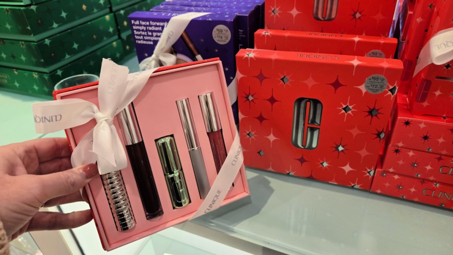 hand holding a clinique gift set next to other packaging
