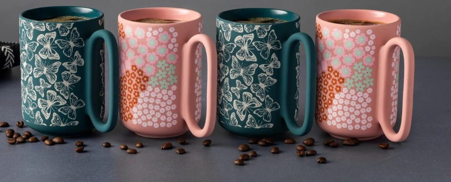 four pink and green coffee mugs with coffee beans in front of them