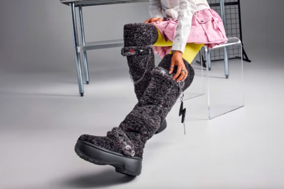 woman in pink skirt sitting wearing black leopard boots