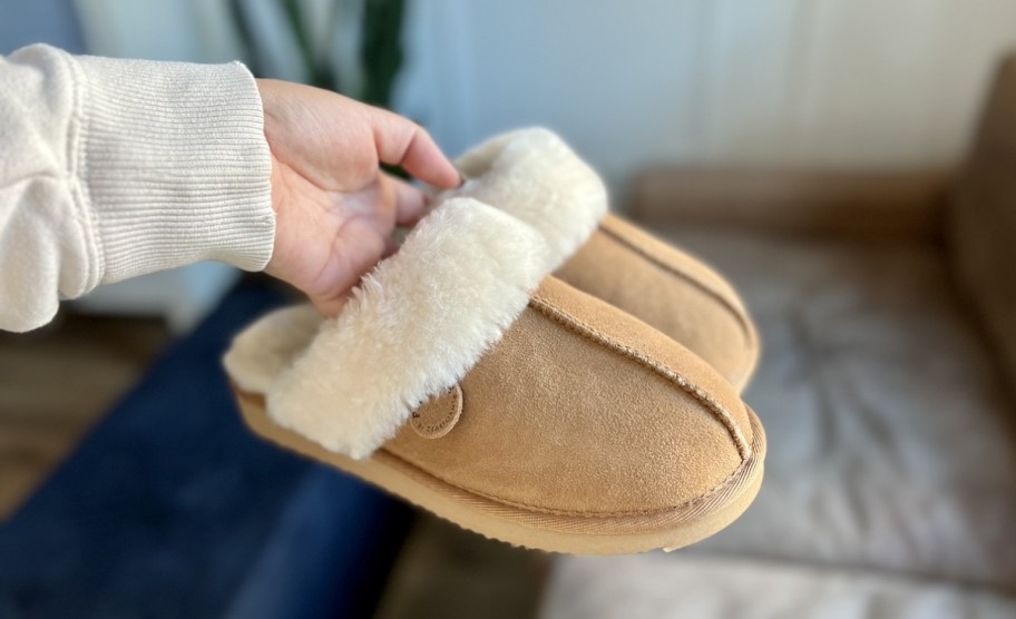 womans hand holding a pair of slippers