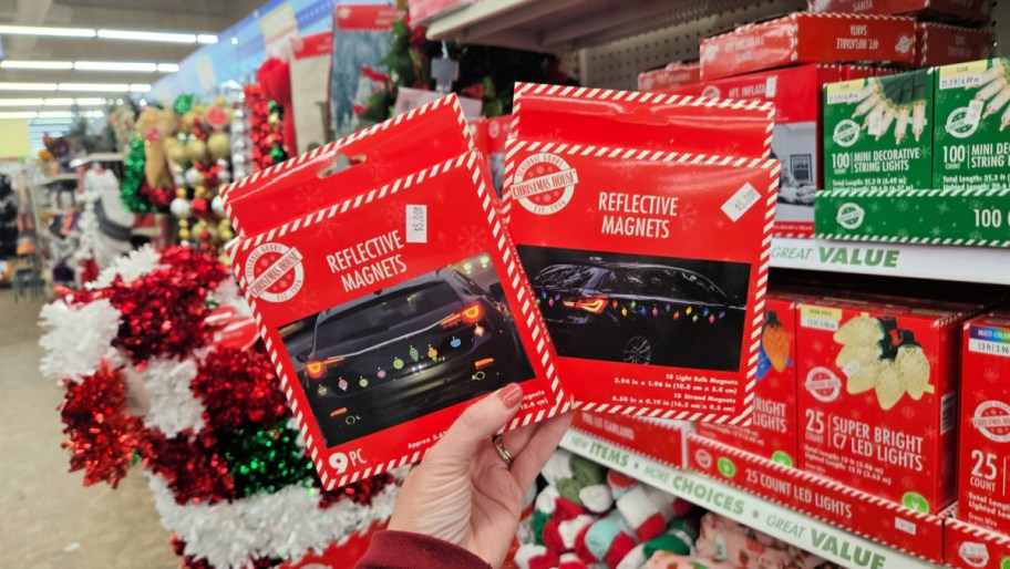 hand holding two packages of christmas reflective car magnets in a dollar tree store aisle