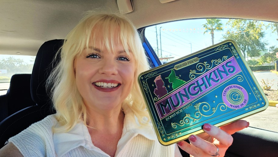 smiling woman holding a dunkin wicked munchkins tin