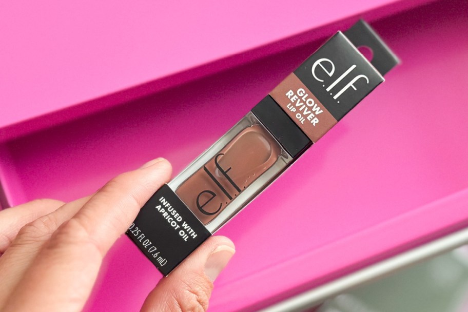 hand holding lip oil over pink toolbox