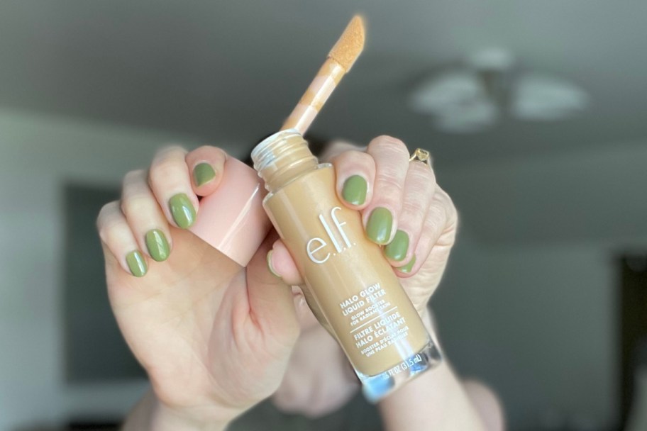 hands holding liuid concealer wand sticking out