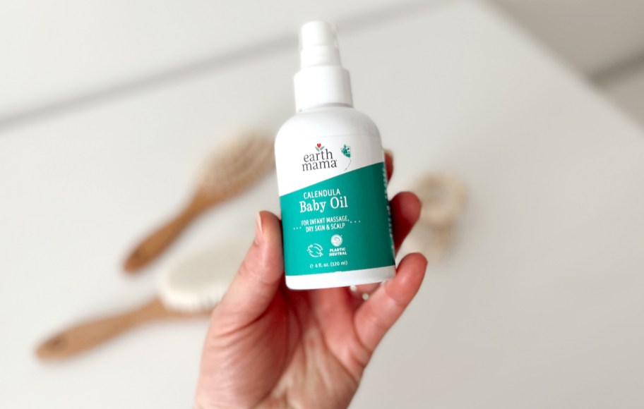 hand holding a bottle of earth mama calendula baby oil