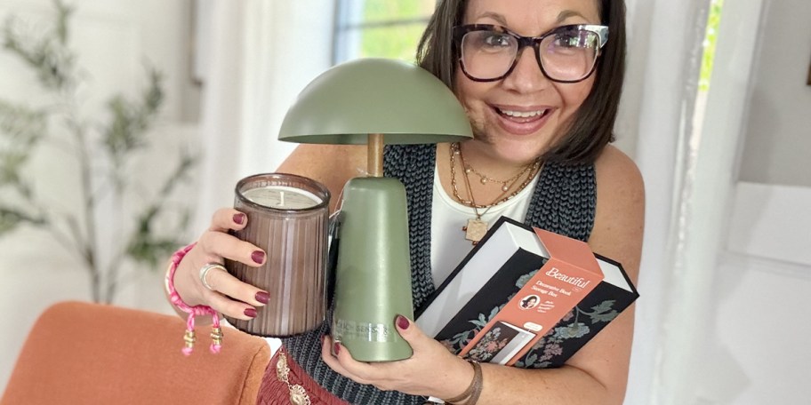 woman holding candle, green lamp, and book 