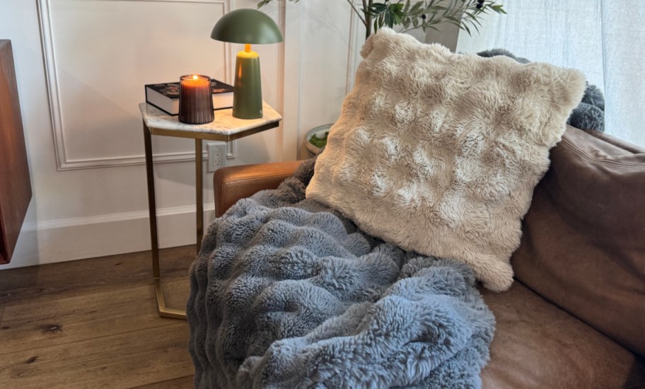 faux fur pillow and blanket on a couch, next to an end table