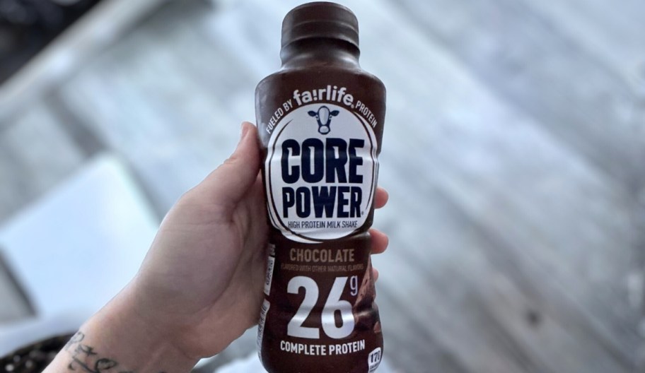 a hand holding a bottle of chocolate protein shake