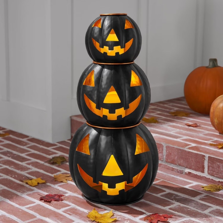 3 black metal jacko lanterns in a stack on a porch