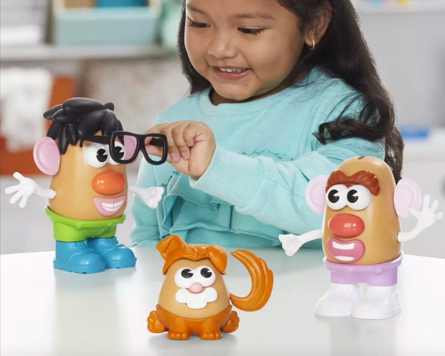 girl playing with three potato heads