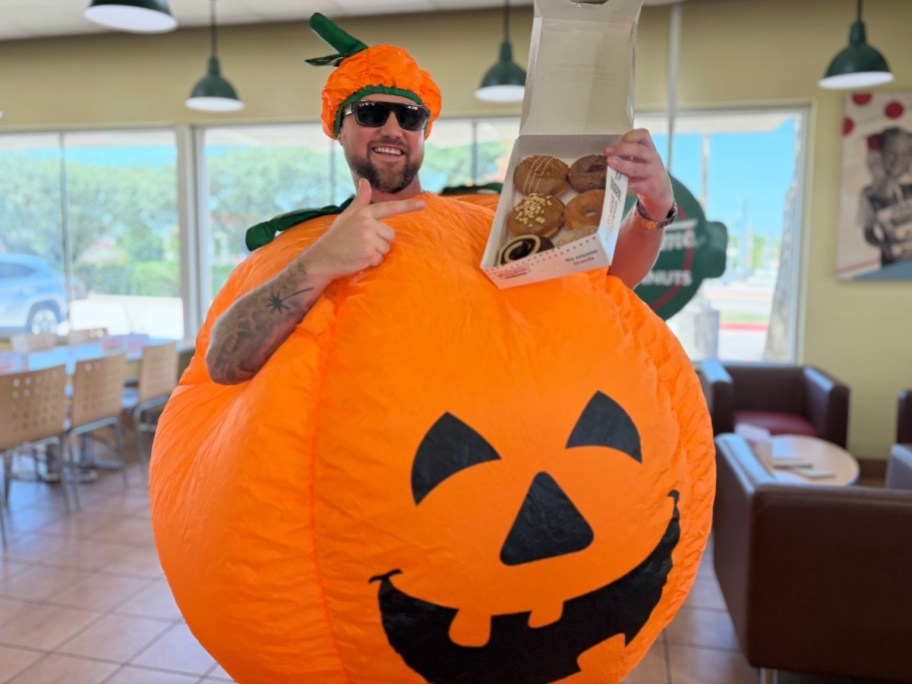 man in pumpkin costume holding doughnuts