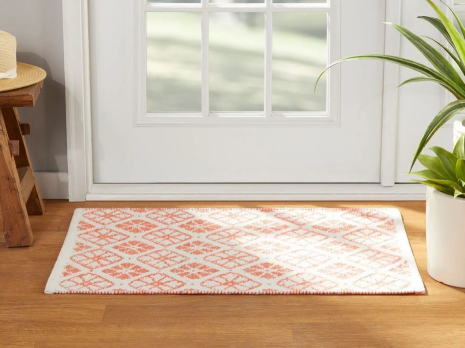 pink and white patterned Mainstays by Becky G. & Alejandra Indoor Accent Rug in front of door