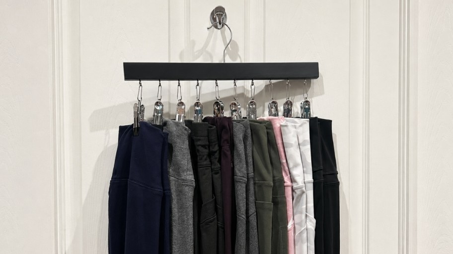 a leggings organizer hanging from a coat hook with pairs of leggings