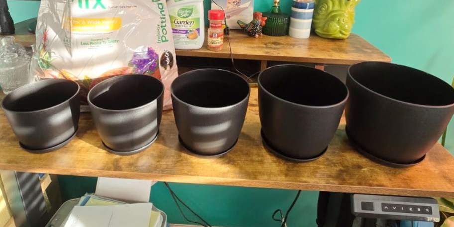 5 black planter pots on table