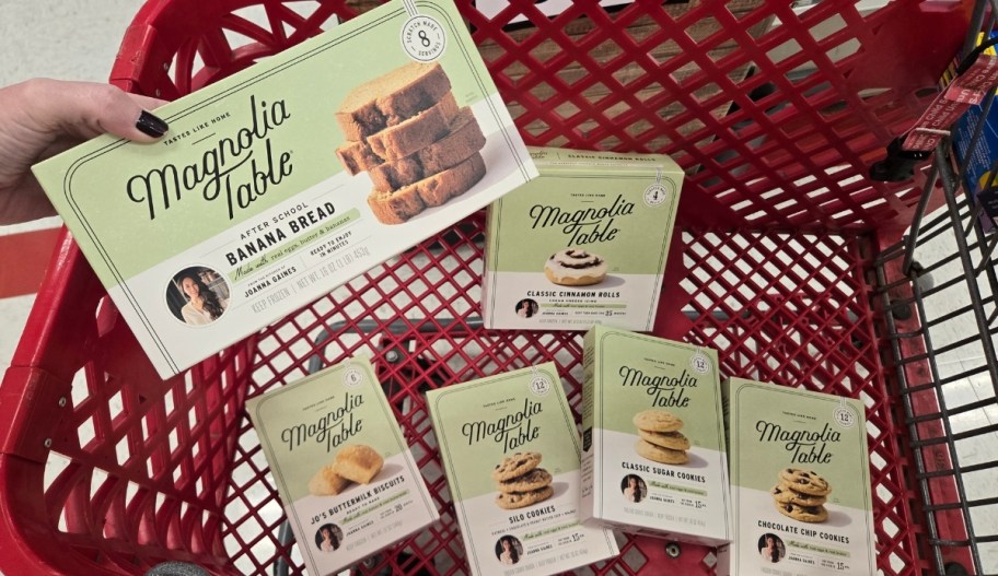 a womans hand holding a box of banana bread above a shopping cart filled with other boxes of frozen baked goods