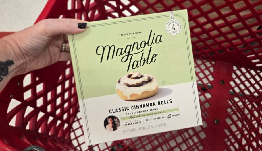 womans hand holding a box of frozen cinnamon rolls