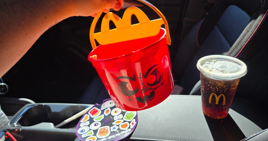 red McDonald's boo bucket held over stickers and soda cup in a car