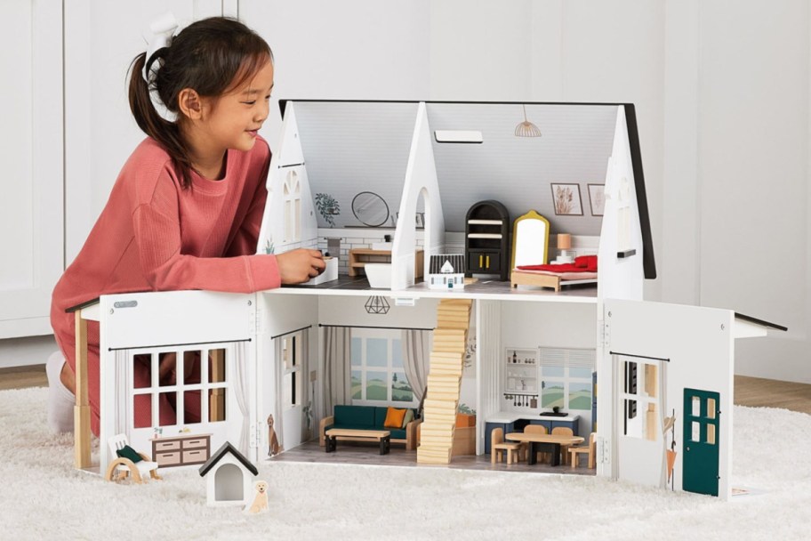 little girl playing with a farmstyle dollhouse