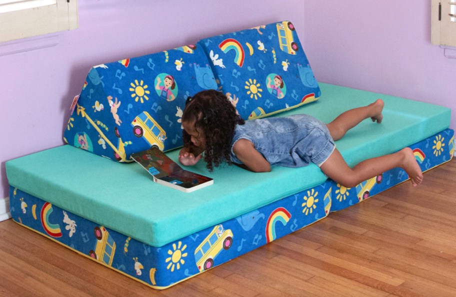girl laying on blue couch with rainbows and busses on it