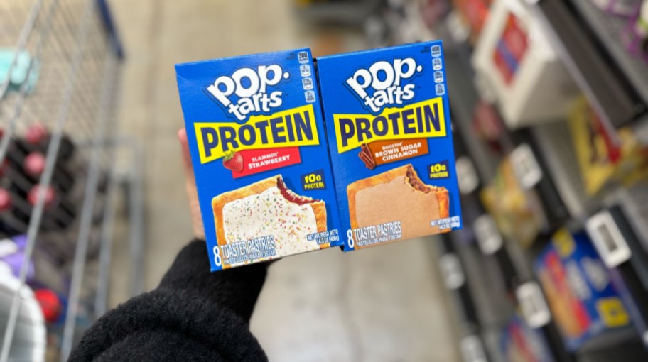 hand holding two boxes of pop tarts protein in a store aisle