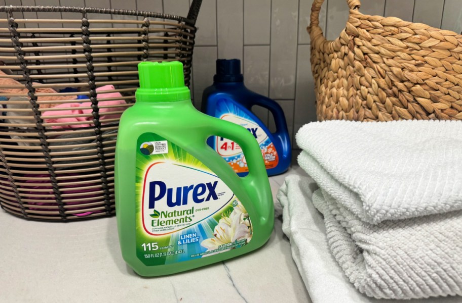purex detergent sitting next to towels and laundry baskets