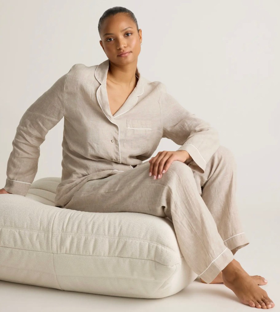woman wearing natural beige colored pajamas sitting on cream cushion