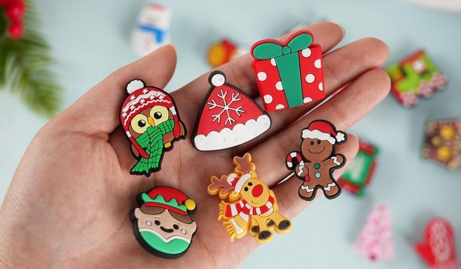 a mans hand holding 6 holiday shoe charms
