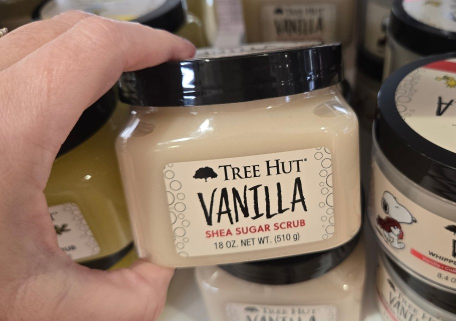 womans hand holding a jar of sugar scrub