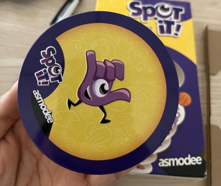 hand holding spot it card game tin